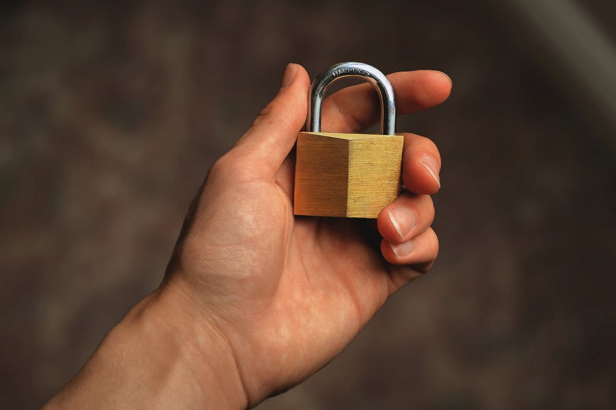 Hand holding a brass padlock, symbolizing security and protection