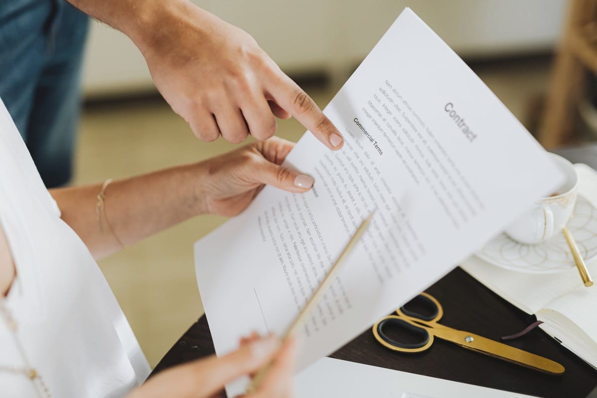 Close-up of two people discussing a business contract at a desk in an office setting.
