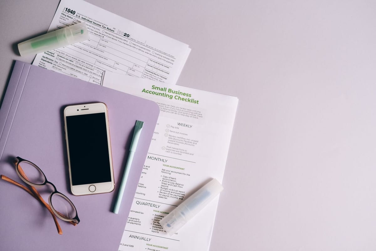 Flat lay of accounting documents, smartphone, and glasses on a desk.